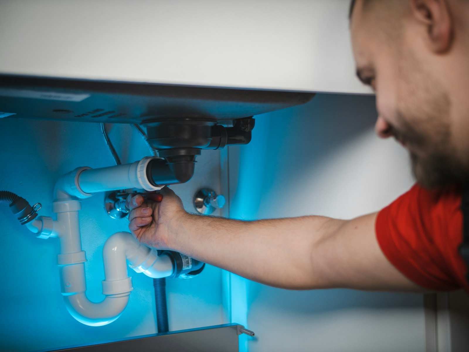 Plumber repairing pipes under a bathroom sink